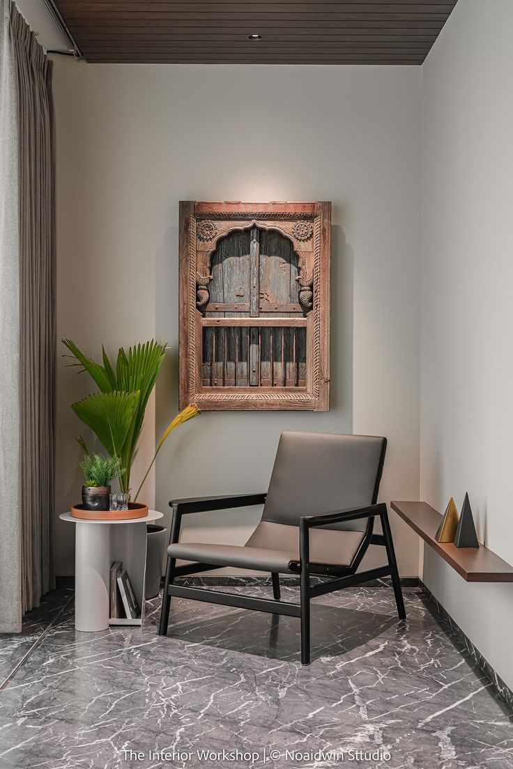 a chair sitting next to a potted plant in front of a painting on the wall