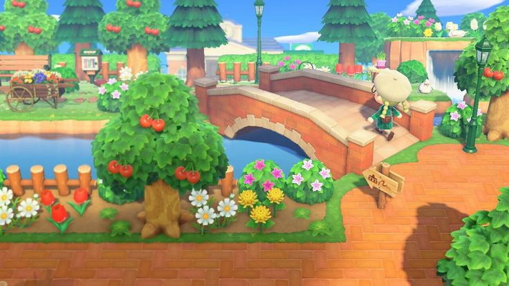 an animal crossing a bridge over a small pond in the middle of a park with lots of trees and flowers