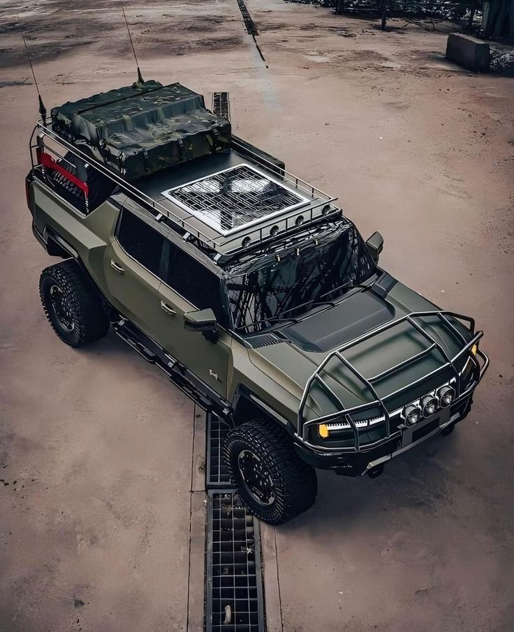 an army truck parked in the middle of a parking lot with its hood up and luggage on top