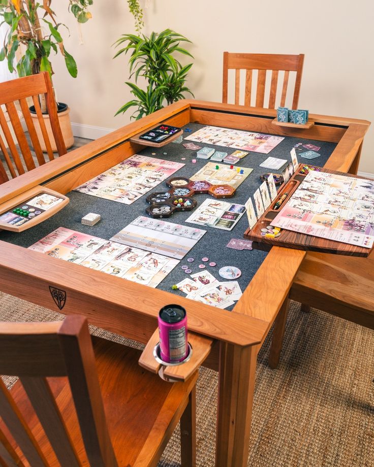 a wooden table topped with lots of cards next to two chairs and a potted plant