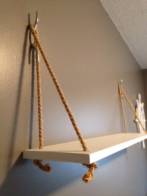 a white shelf with rope hanging from it