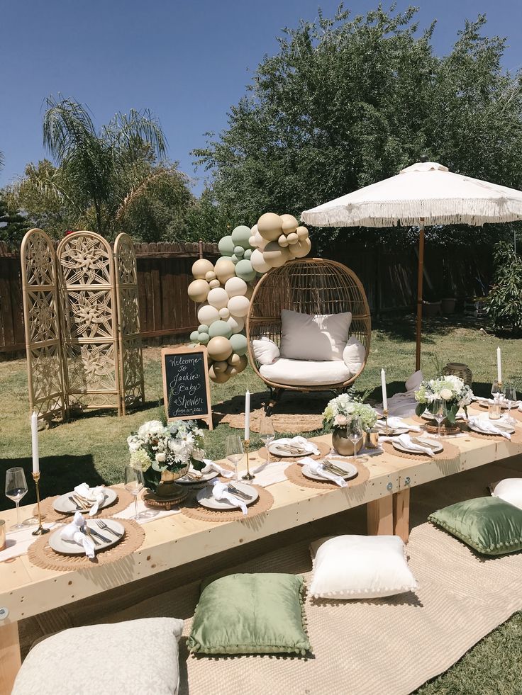 a table set up for a party with white and green decorations, balloons and plates