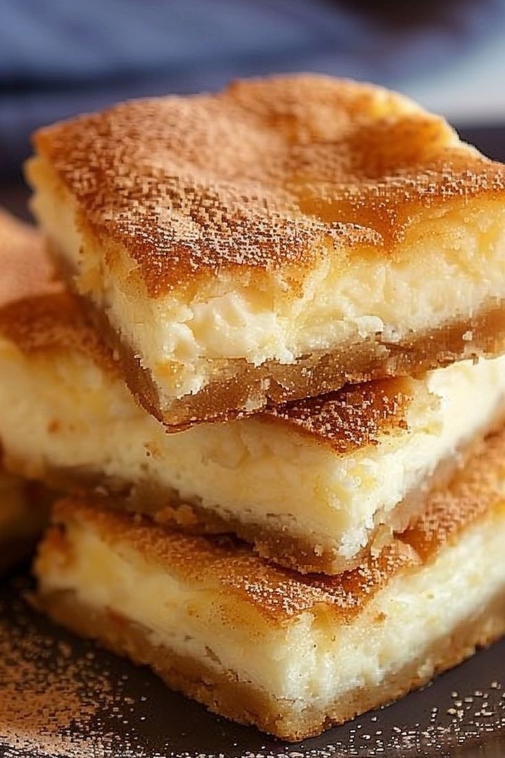 three pieces of cake sitting on top of a black and white plate with powdered sugar