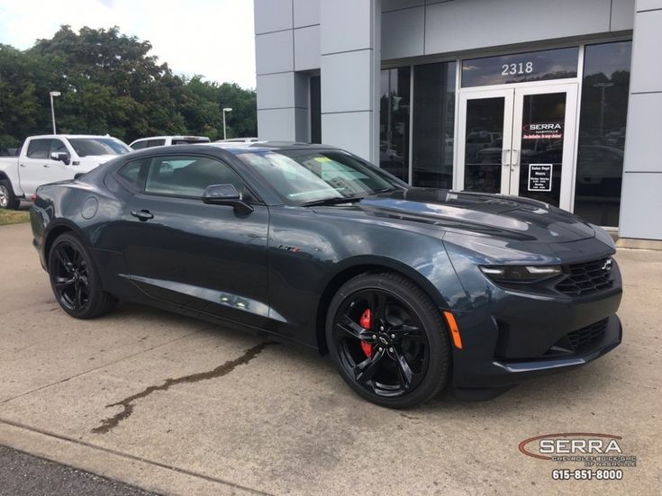 a gray chevrolet camaro is parked in front of a building