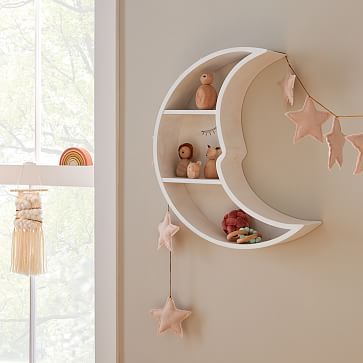 there is a shelf on the wall that has stars and moon decorations hanging from it