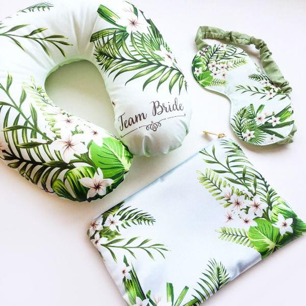 a white and green floral print neck pillow with matching headband, tie and handkerchief