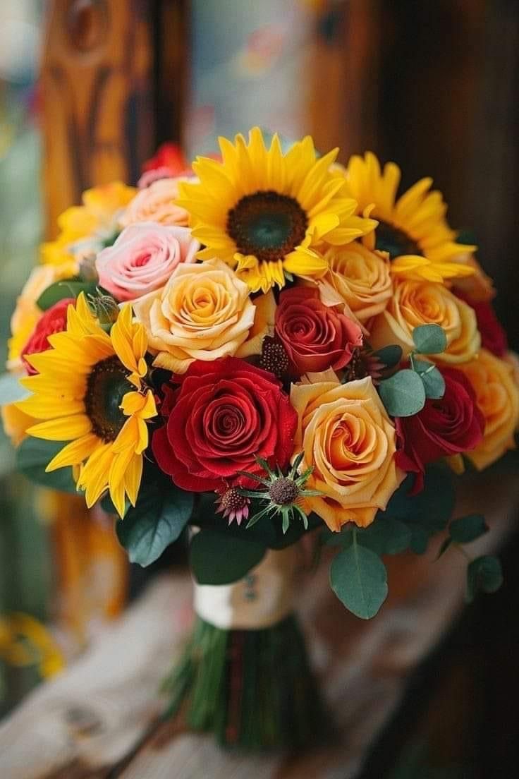 a bouquet of sunflowers and roses on a bench