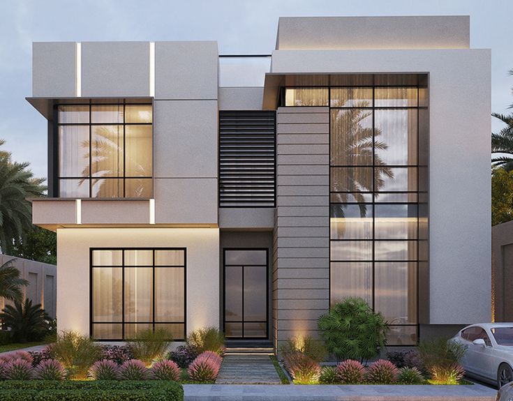 a modern style house with lots of windows and plants in the front yard at dusk