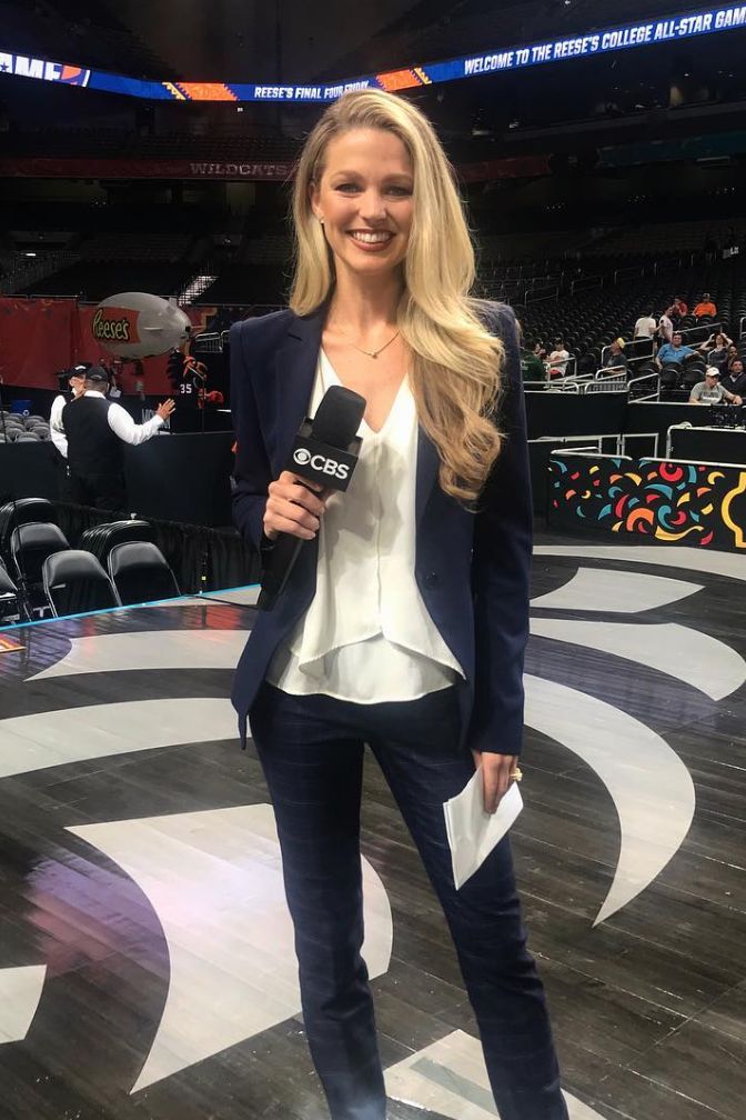 a woman is holding a microphone and standing in front of a large screen at a sporting event