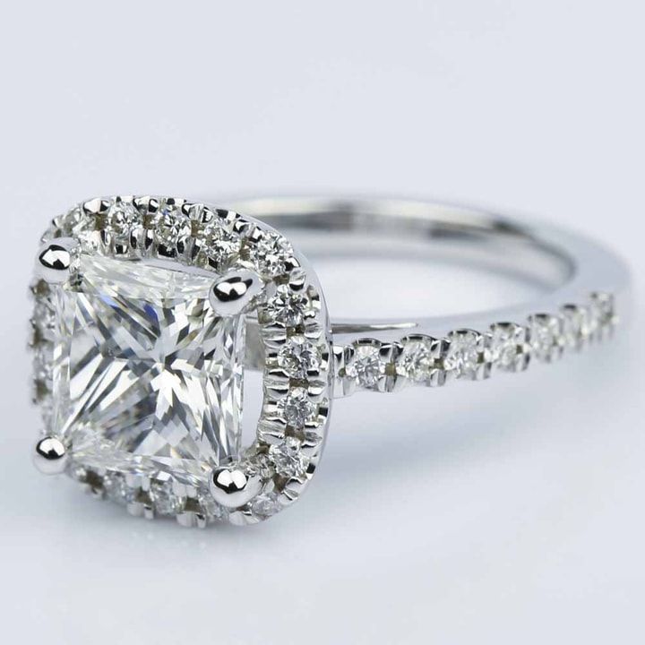 an engagement ring with a cushion cut diamond surrounded by pave diamonds