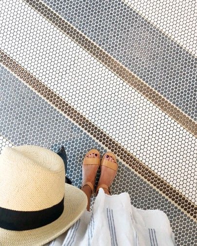 a person wearing sandals and a hat standing in front of a tiled floor