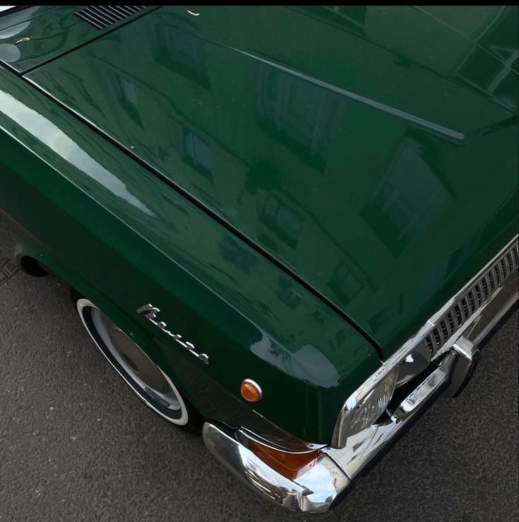 the front end of an old green car with chrome rims and grill grilles