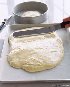 a person cutting dough with a knife on top of a tray next to a pan