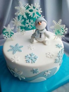 a frosted cake decorated with snowflakes and a small figure on the top