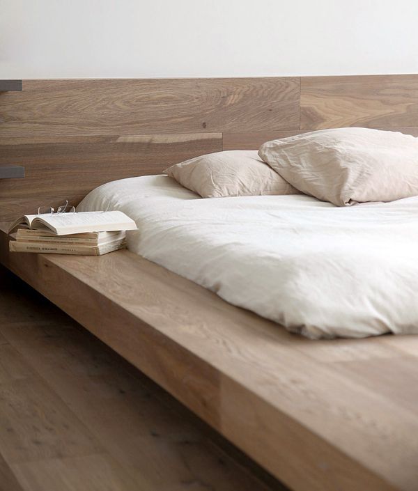 a wooden bed with white sheets and pillows