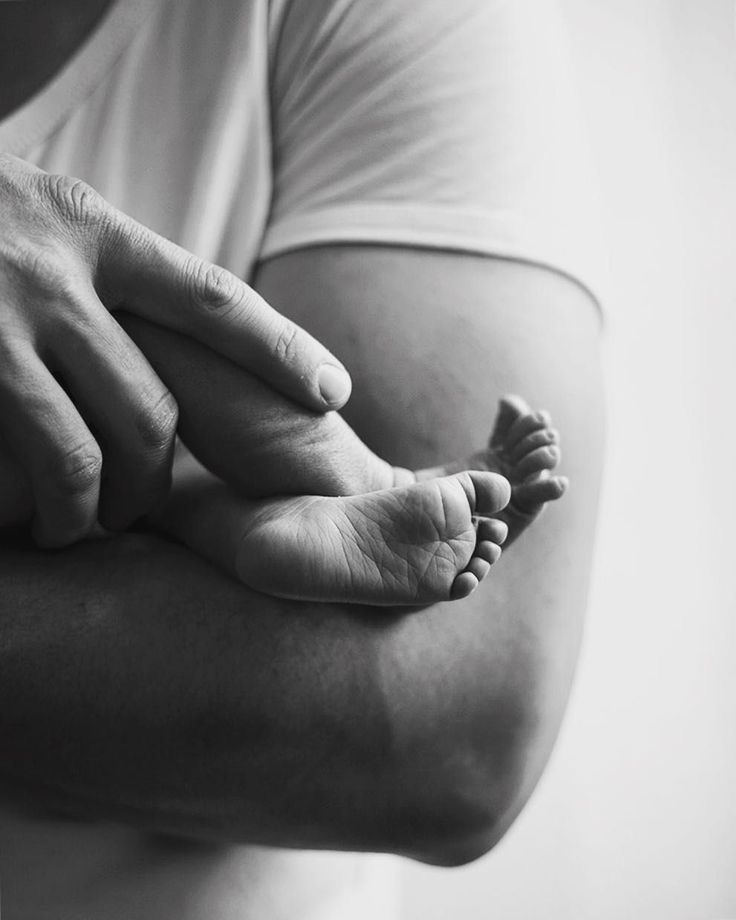 a black and white photo of a person holding a baby's foot in their arms