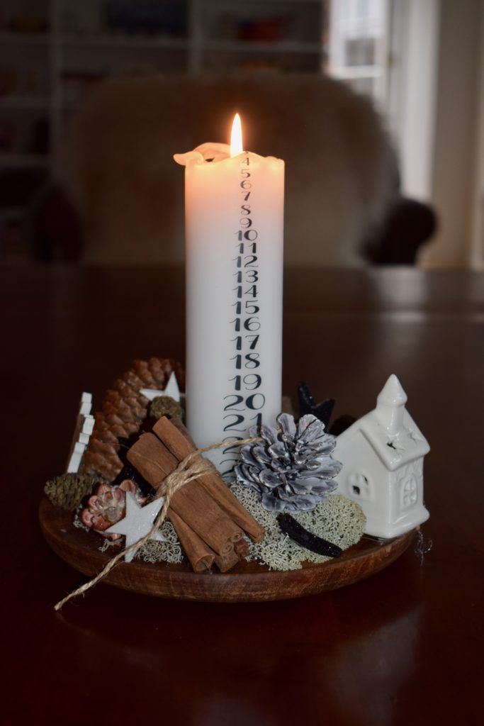 a lit candle sitting on top of a wooden plate filled with cookies and other items