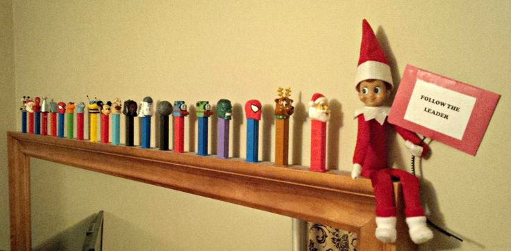 an elf is sitting on top of a shelf with many pens and pencils in front of him