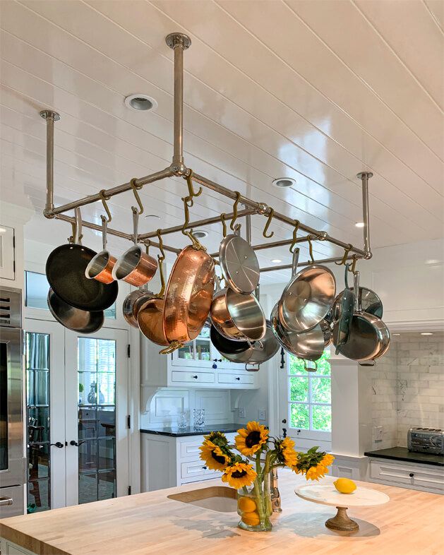 pots and pans hanging from the ceiling in a kitchen with sunflowers on the counter