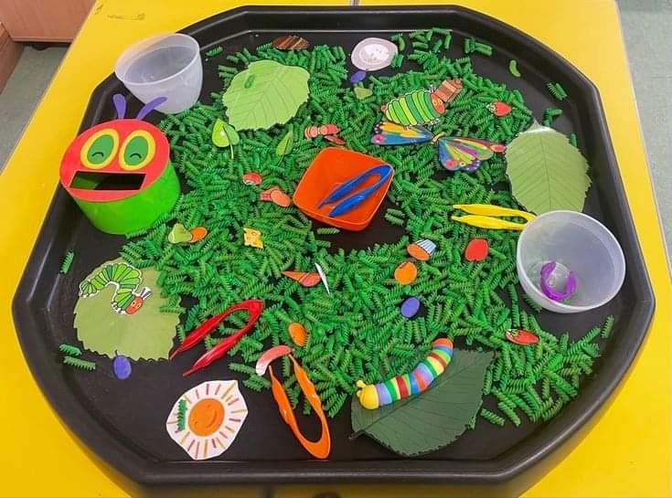 a black tray filled with green plants and plastic cups sitting on top of a yellow table