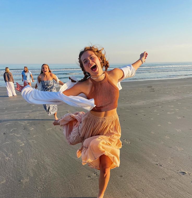 a woman is dancing on the beach with other people