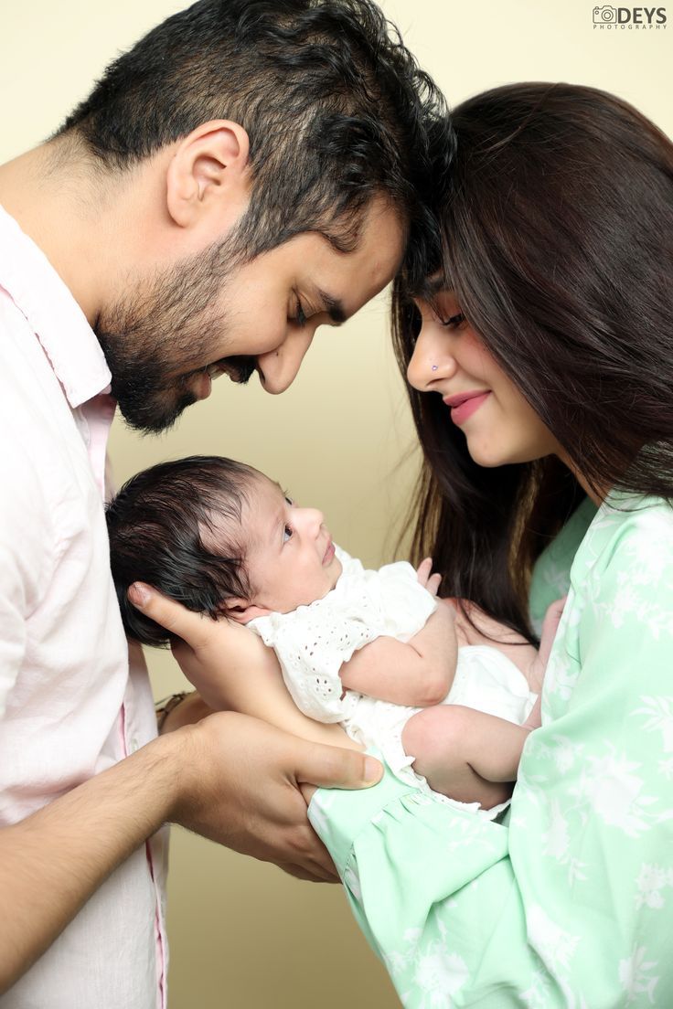 a man and woman holding a baby in their arms