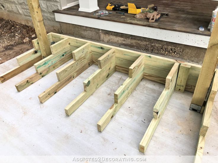 some wooden boards are laying on the ground near a porch and steps in front of a house