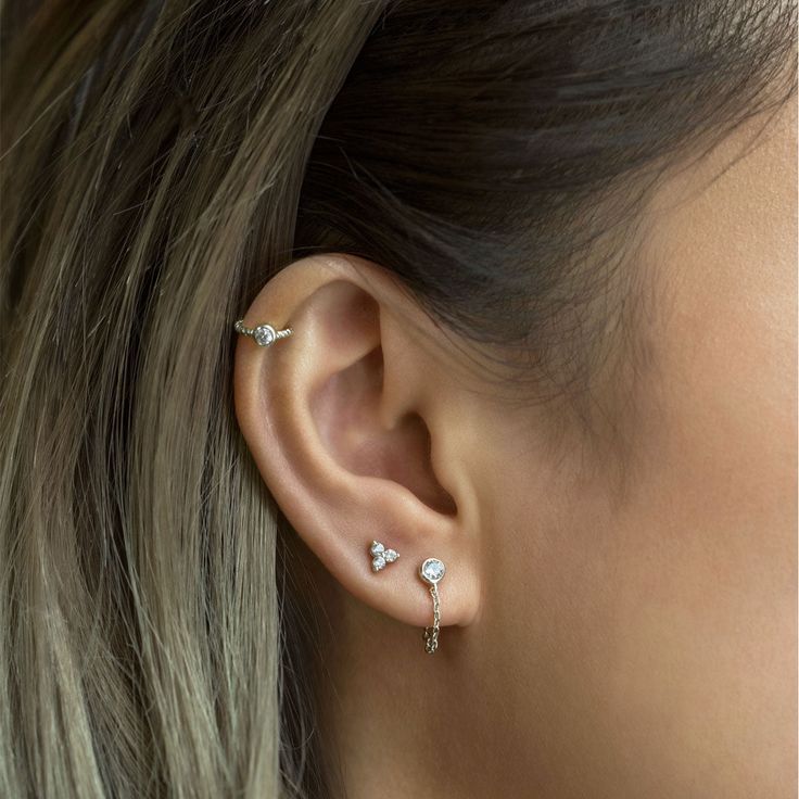 a close up of a woman's ear with three small diamond studs