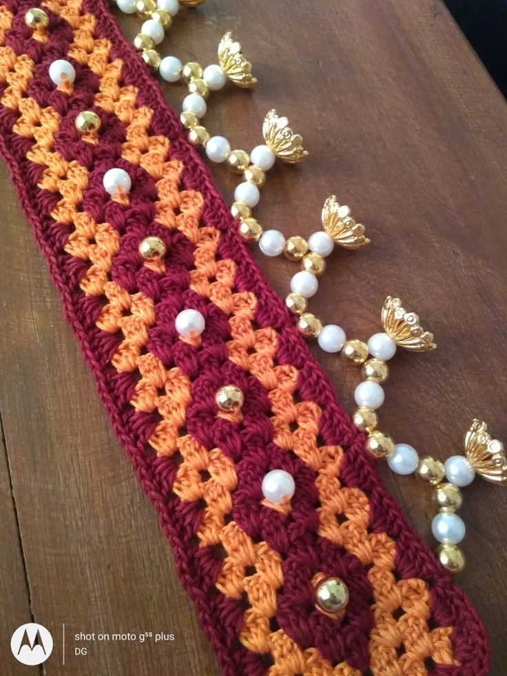 crocheted table runner with beads and pearls on the edge, sitting on a wooden surface