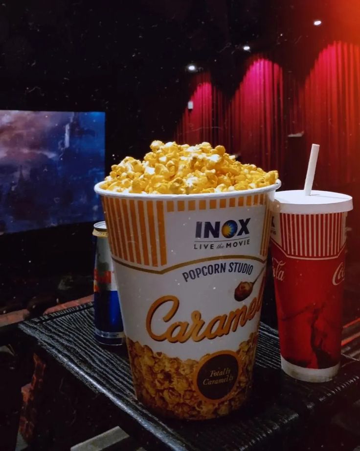 two cups of popcorn sit next to each other on a table in front of a television