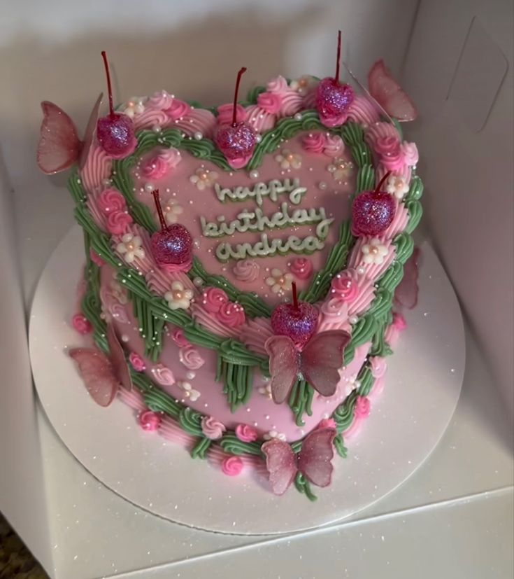 a heart shaped birthday cake with butterflies on it's side and the words happy birthday written in pink frosting