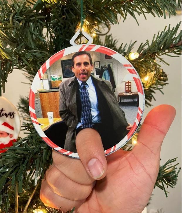 a hand holding a christmas ornament with a man in a suit on it