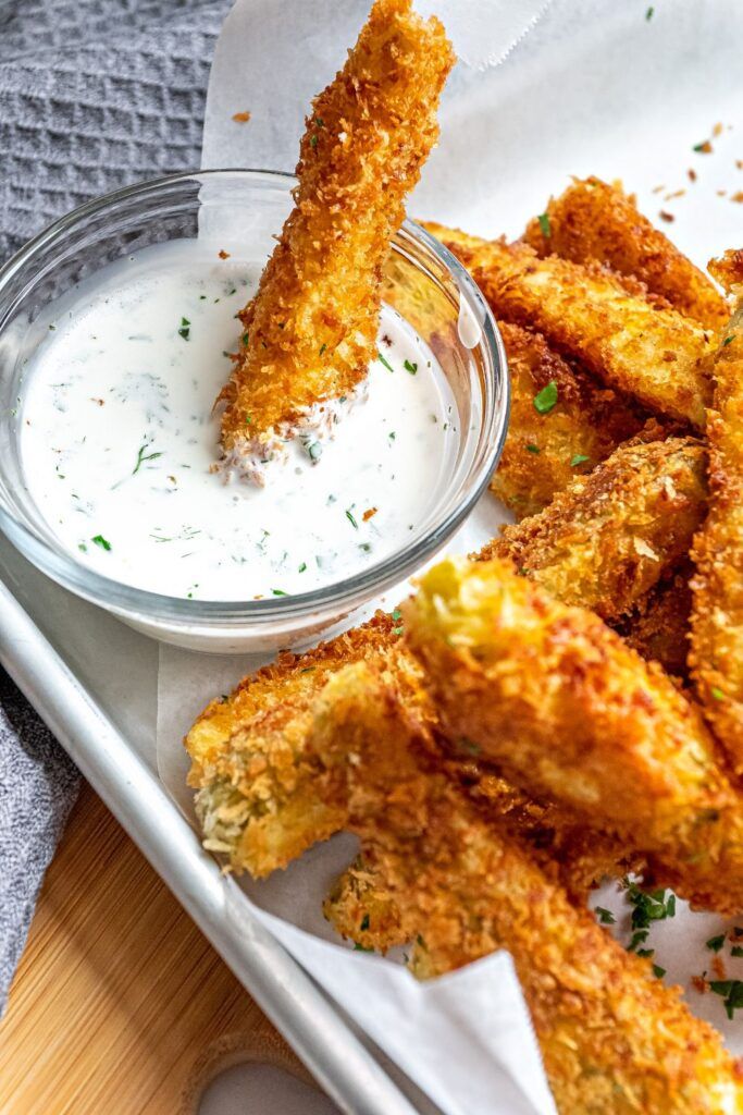 some fried food is in a bowl on a tray next to a cup of ranch dressing