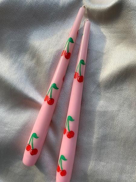 two pink toothbrushes with cherries on them sitting next to each other in front of a white sheet