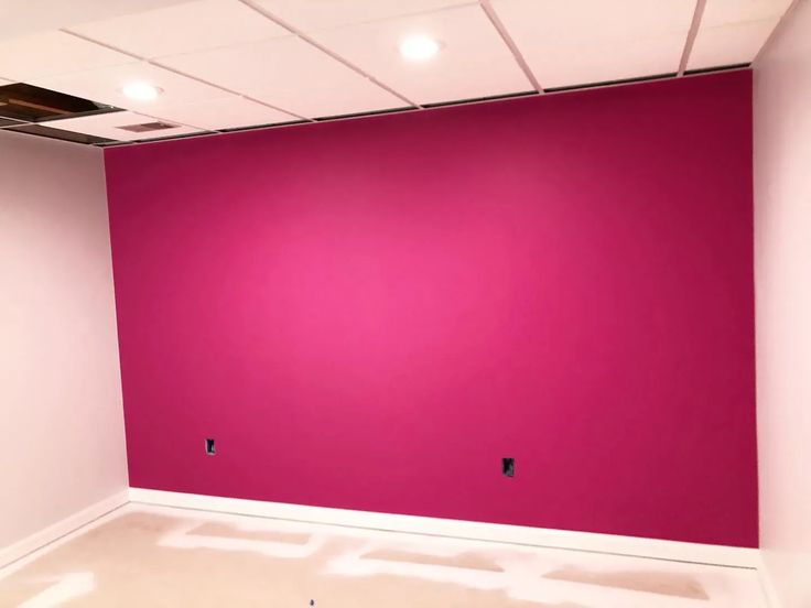 an empty room with pink walls and white flooring in the center is being painted