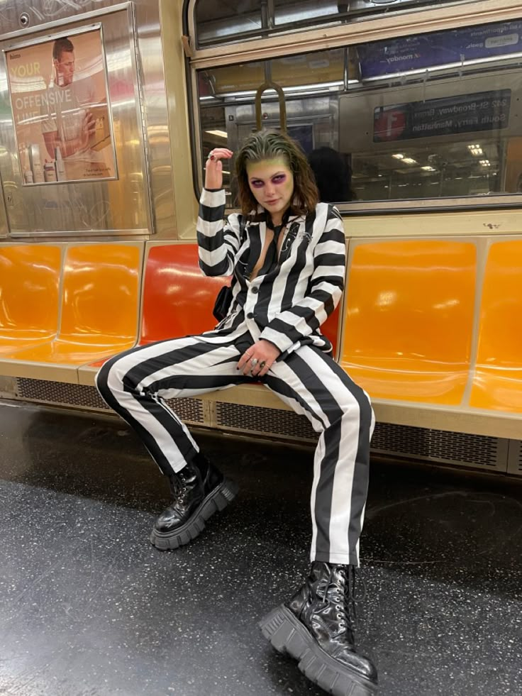 a woman sitting on top of a bench next to an orange train car in a subway