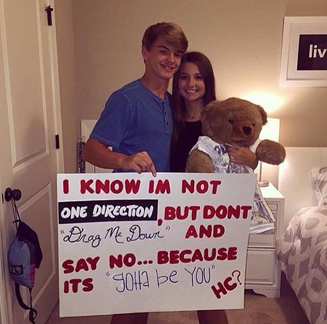 a man and woman holding a teddy bear in front of a sign that says i know i'm not one direction, but don't say no because it is 10 minutes