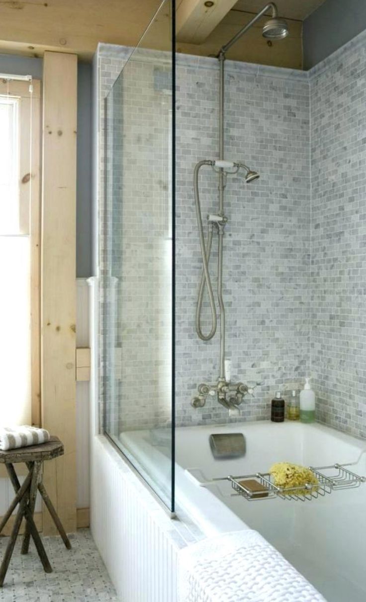 a bath tub sitting next to a window in a white tiled bathroom with gray walls