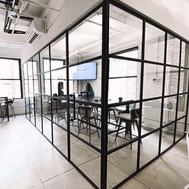 an office with glass walls and people sitting at desks in the middle of it