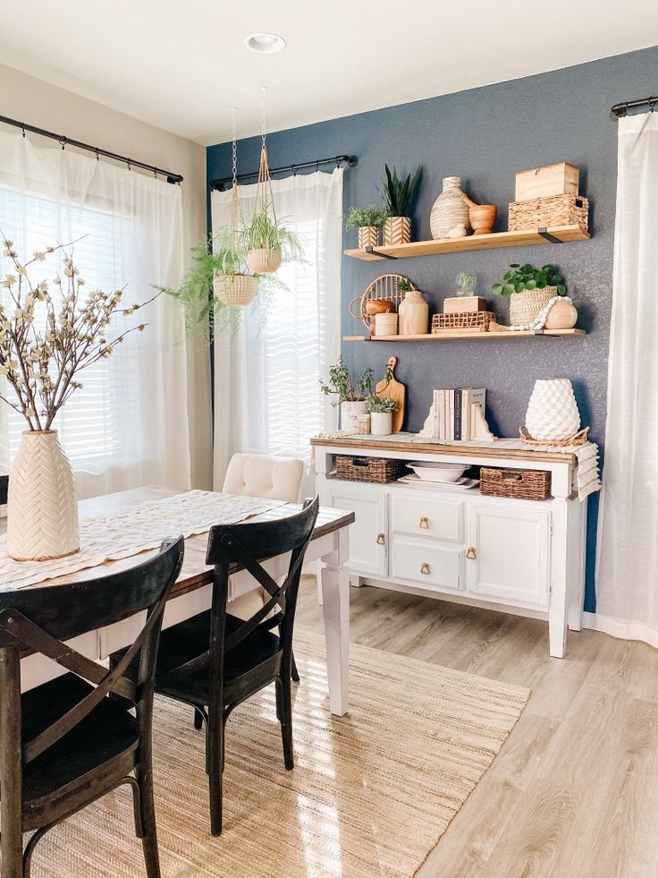 a dining room table with chairs and shelves on the wall behind it, along with other furniture