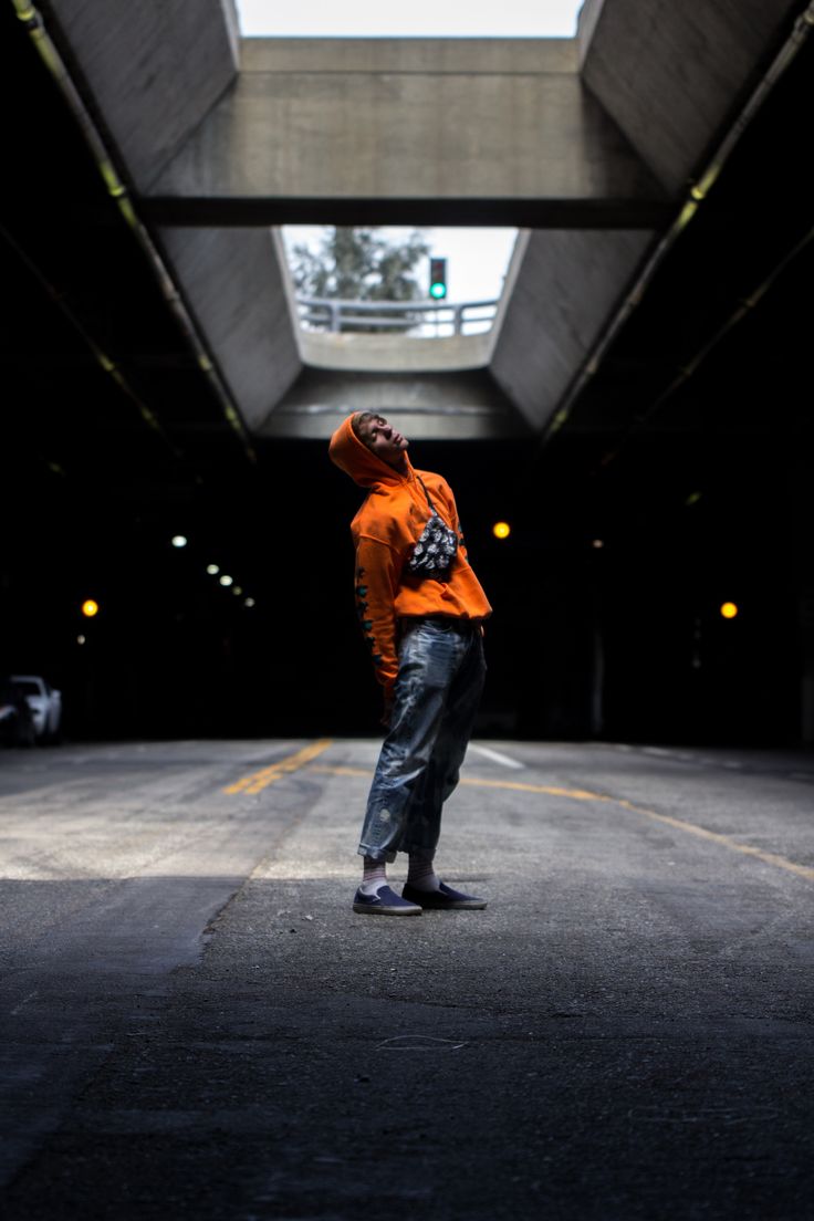 a man standing in the middle of an empty parking garage with his hands up to his head