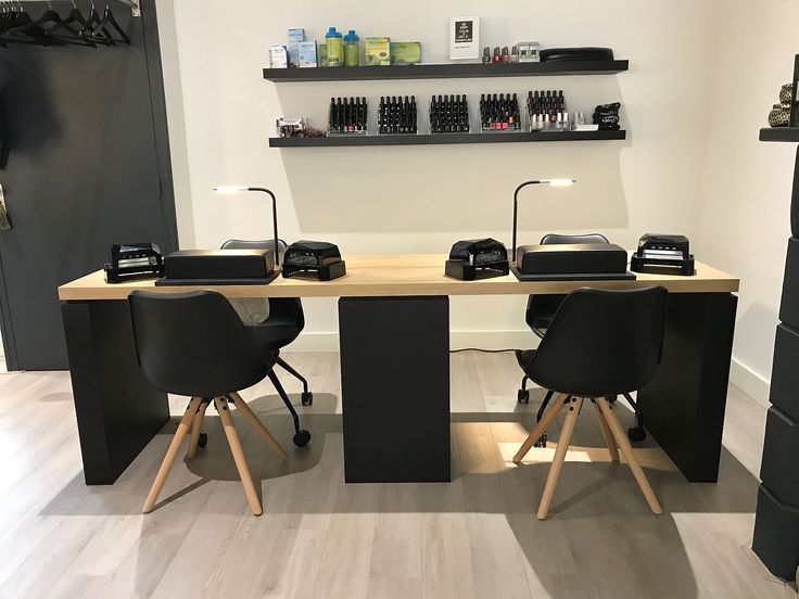 two black chairs sitting at a desk in front of a shelf with hair products on it