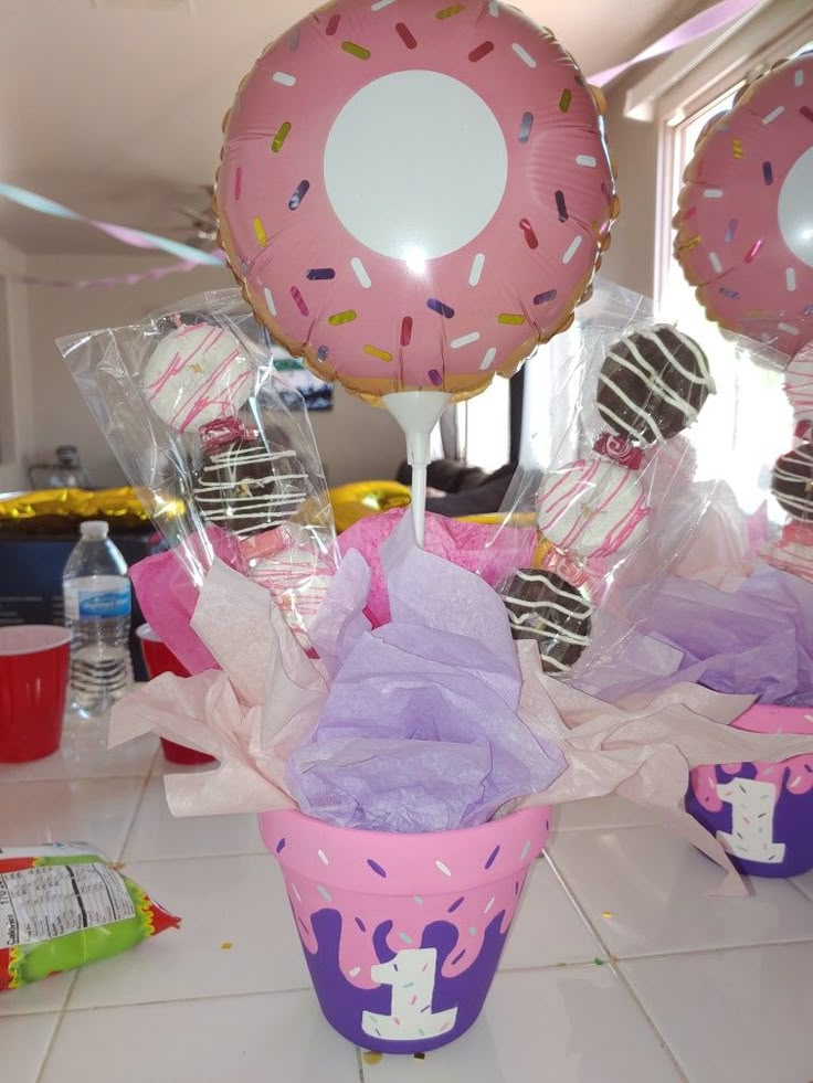 pink and purple cupcakes with sprinkles on them in front of balloons