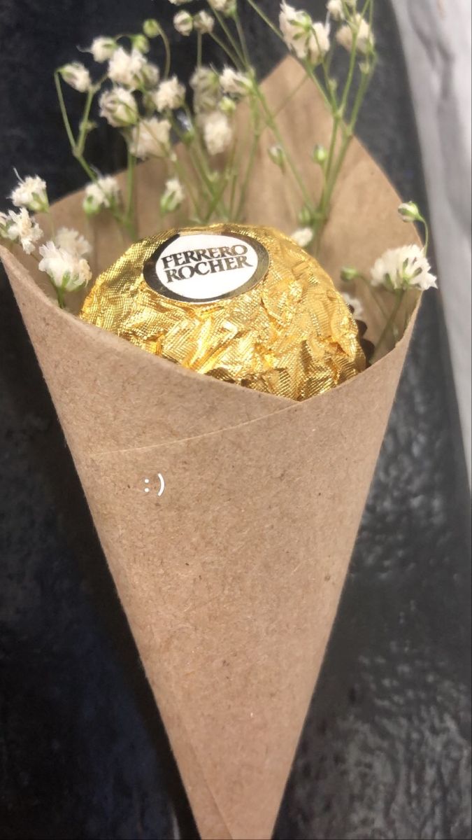 a brown paper cone filled with flowers and a piece of chocolate