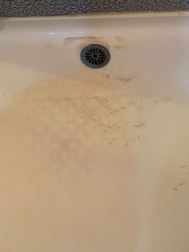 a dirty sink with water running down the drain and dirt on the floor below it