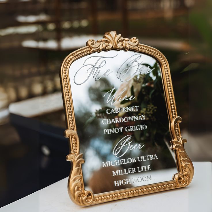 an ornate gold framed mirror with the names of each wedding guests and date on it