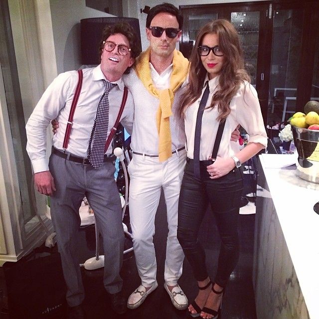 two men and a woman posing for a photo in front of a kitchen counter top