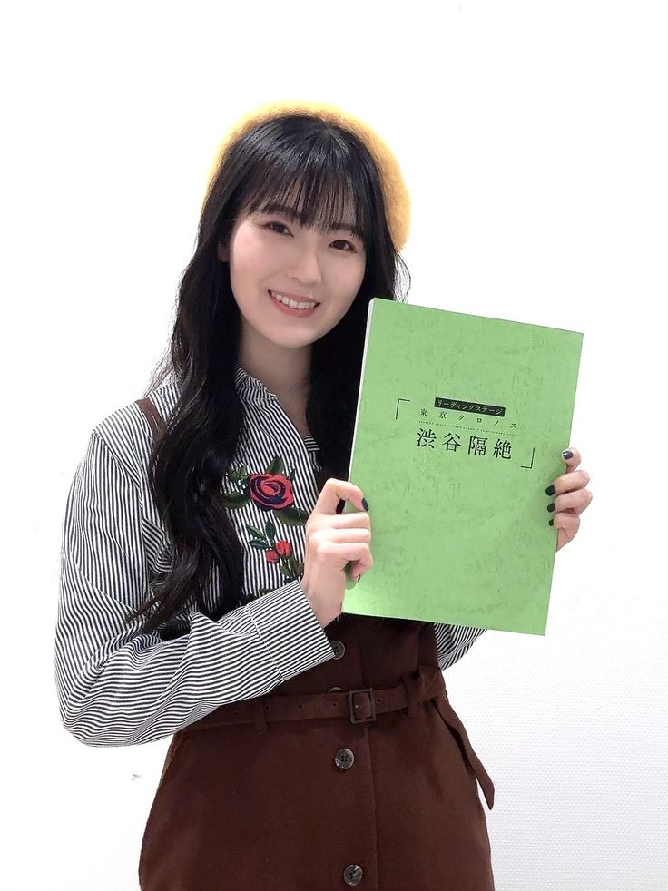 a woman holding up a green piece of paper with writing on it and smiling at the camera