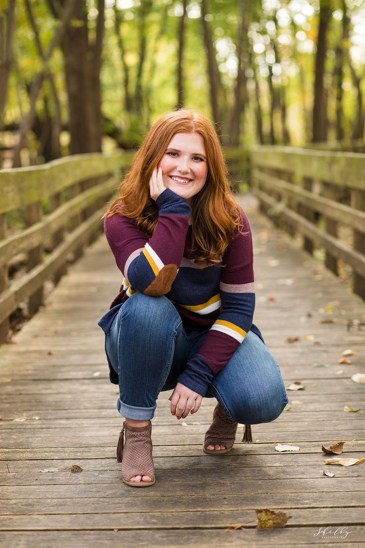 a woman kneeling down on a wooden bridge