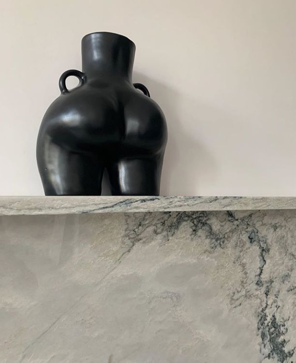 a large black vase sitting on top of a marble countertop next to a sculpture